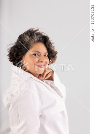 A woman with a white shirt and a gold hoop earring is smiling A woman with a white shirt and a gold hoop earring is smiling 133702153