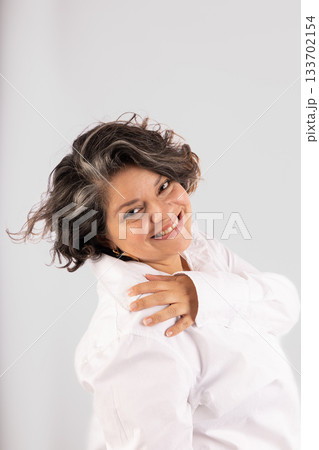 A woman with grey hair is smiling and wearing a white shirt A woman with grey hair is smiling and wearing a white shirt 133702154