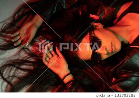 A woman with long hair is laying on the ground in a red room A woman with long hair is laying on the ground in a red room 133702188