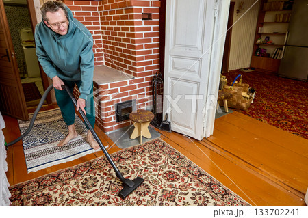 Refreshing surface as homeowner uses vacuum in room with stove heating, creating tidy environment during regular household routine. 133702241