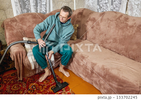 Man cleaning vacuum cleaner hose inside, separating parts for inspection, working on hose maintenance. 133702245