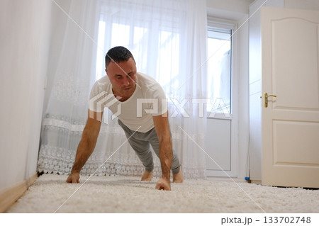 Focused athlete doing a plank exercise by the sea, demonstrating strength and dedication to fitness 133702748
