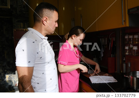 Father and daughter cooking pasta in the kitchen. Family values: dining together at home with family. Yellow kitchen. Modern interior. Father and daughter cooking pasta in the kitchen. Family values: dining together at home with family. Yellow kitchen. Modern interior. 133702779