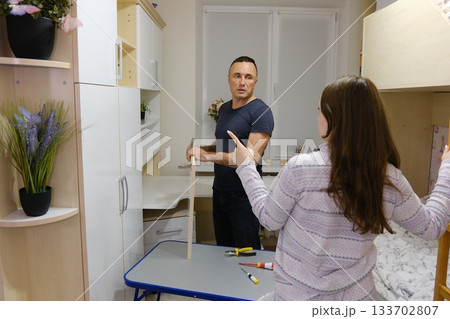 A father repairs a closet door in his daughter's room. Family values: good parent-child relationships. A video set showing the process of repairing a cabinet door 133702807