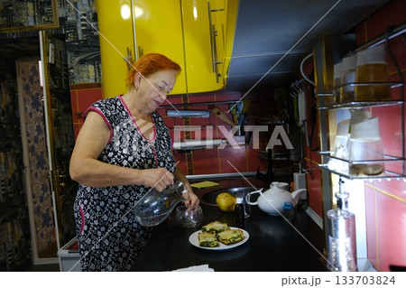 Woman pouring water with plastic into glass on blue background, closeup. Microplastic Awareness Month 133703824