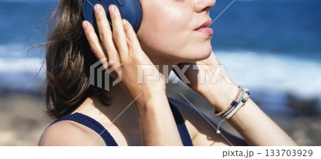 A girl with a wireless headphones, is listening music outdoors. A girl with a wireless headphones, is listening music outdoors. 133703929