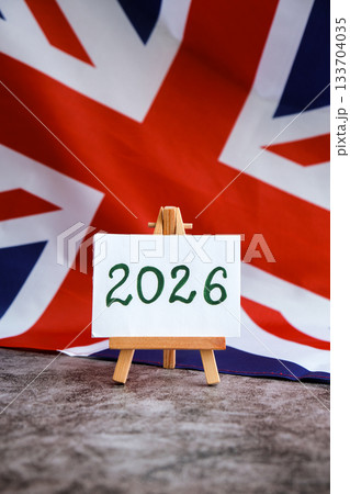 Paper note with text 2026 on National symbol of Great Britain. British wave the UK silky flag background. Financial outlook planning, new year annual report 133704035