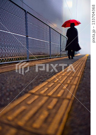 雨の日に、歩道を歩く女性 雨の日に、歩道を歩く女性 133704368