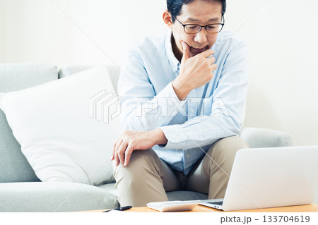 リビングでパソコン操作をする中高年男性 リビングでパソコン操作をする中高年男性 133704619