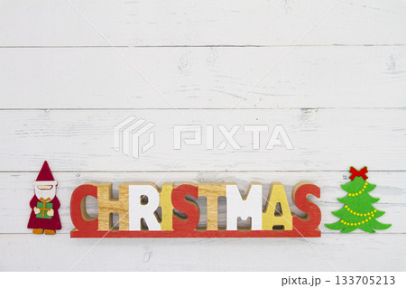 白い木目の背景に置かれた「CHRISTMAS」の文字オブジェとサンタ、ツリーの飾り 白い木目の背景に置かれた「CHRISTMAS」の文字オブジェとサンタ、ツリーの飾り 133705213