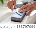 キッチンで包丁研ぎの男性の手元 133707099