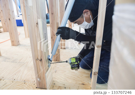 制震ダンパーを取り付ける大工さん 133707246