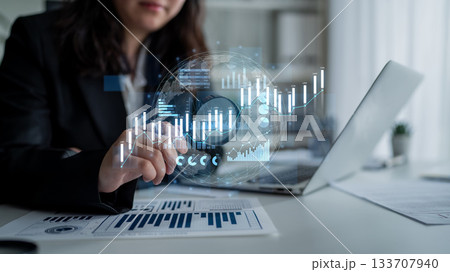 Business professional analyzing digital financial charts with modern technology in a bright office setting, showcasing trends and data visualization Scalp 133707940