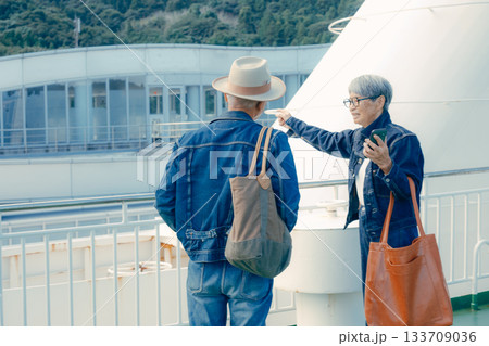フェリーの甲板で港町を眺めるシニア夫婦の旅行ポートレート 133709036
