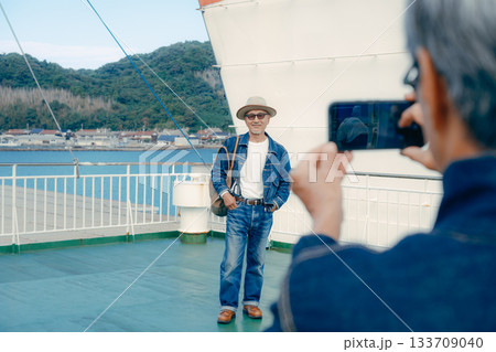 フェリーの甲板で港町を眺めるシニア夫婦の旅行ポートレート 133709040