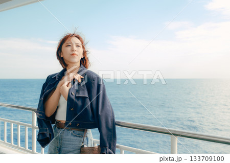 フェリーの甲板で海風を感じる20代女性の旅行シーン 133709100