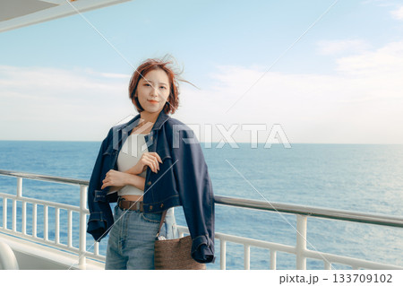 フェリーの甲板で海風を感じる20代女性の旅行シーン 133709102