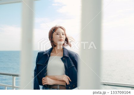 フェリーの甲板で海風を感じる20代女性の旅行シーン フェリーの甲板で海風を感じる20代女性の旅行シーン 133709104