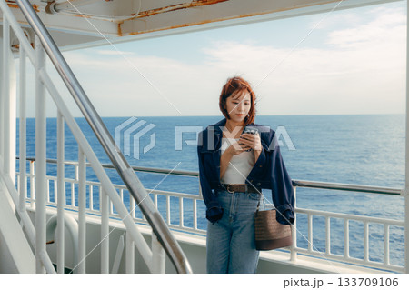フェリーの甲板で海風を感じる20代女性の旅行シーン フェリーの甲板で海風を感じる20代女性の旅行シーン 133709106