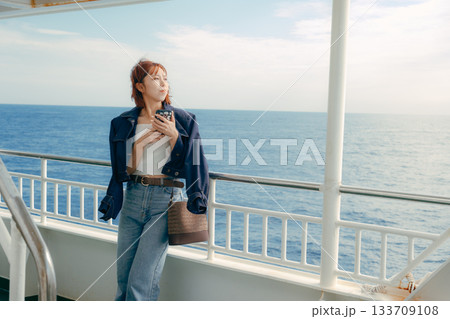 フェリーの甲板で海風を感じる20代女性の旅行シーン フェリーの甲板で海風を感じる20代女性の旅行シーン 133709108