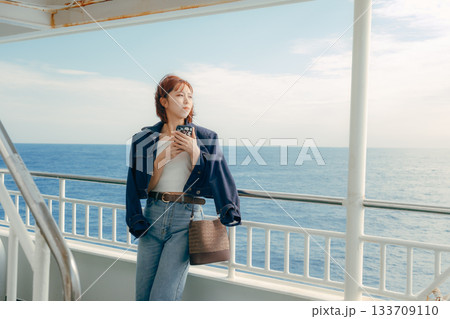 フェリーの甲板で海風を感じる20代女性の旅行シーン フェリーの甲板で海風を感じる20代女性の旅行シーン 133709110