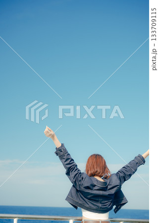 フェリーの甲板で海風を感じる20代女性の旅行シーン 133709115