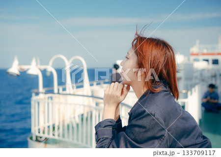 フェリーの甲板で海風を感じる20代女性の旅行シーン フェリーの甲板で海風を感じる20代女性の旅行シーン 133709117