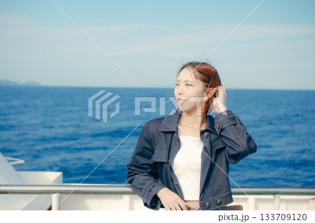 フェリーの甲板で海風を感じる20代女性の旅行シーン フェリーの甲板で海風を感じる20代女性の旅行シーン 133709120
