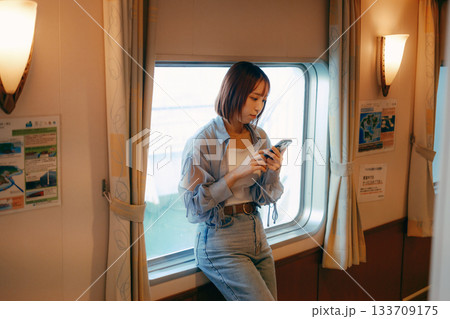 フェリーの船内で窓辺に立つ20代女性の旅行シーン フェリーの船内で窓辺に立つ20代女性の旅行シーン 133709175