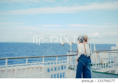 シニア夫婦が船上デッキで景色を指さす旅行シーン シニア夫婦が船上デッキで景色を指さす旅行シーン 133709277
