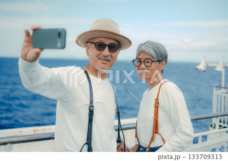 シニア夫婦が船上デッキでセルフィー撮影する旅行シーン シニア夫婦が船上デッキでセルフィー撮影する旅行シーン 133709313