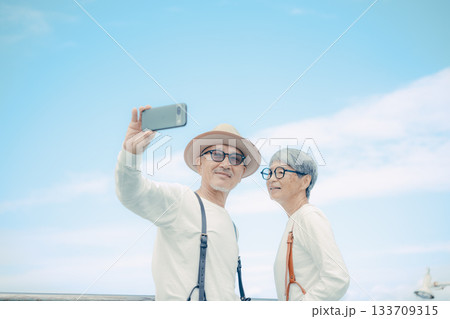 シニア夫婦が船上デッキでセルフィー撮影する旅行シーン シニア夫婦が船上デッキでセルフィー撮影する旅行シーン 133709315