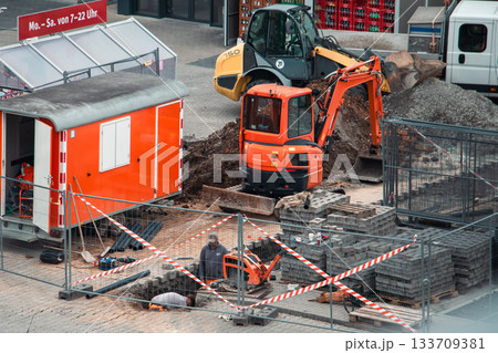 Urban Roadwork Scene with Excavator, Loader, and Construction Worker 133709381