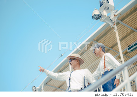フェリーのデッキで景色を眺めるシニア夫婦の旅行シーン 133709413
