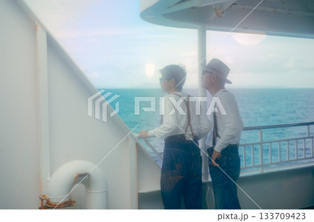 フェリーのデッキで景色を眺めるシニア夫婦の旅行シーン 133709423