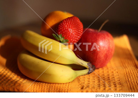 Colorful Fruit Assortment on Orange Fabric Surface Colorful Fruit Assortment on Orange Fabric Surface 133709444