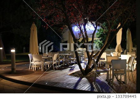 Outdoor Dining Area at Night with Closed Umbrellas and Ambient Lighting 133709445