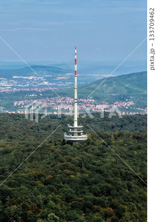 Television tower on forested hill with city view in background 133709462