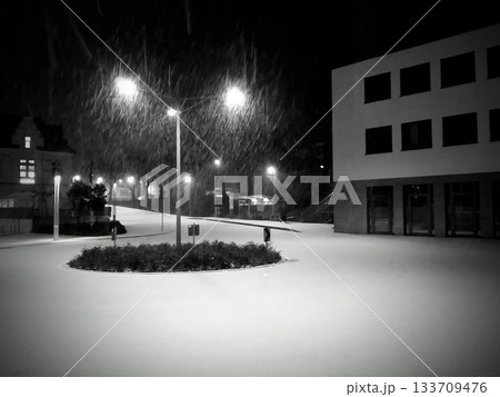 Snowy urban night scene with falling snow and streetlights Snowy urban night scene with falling snow and streetlights 133709476
