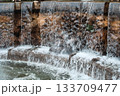 Water cascading over stone spillway into foamy pool 133709477