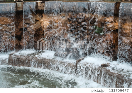 Water cascading over stone spillway into foamy pool Water cascading over stone spillway into foamy pool 133709477