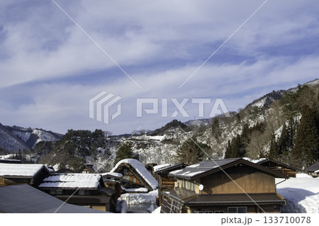 雪の白川郷の合掌造り集落と山々 133710078