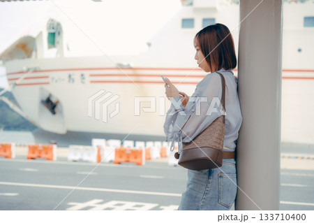 フェリー乗り場でスマートフォンを見る女性 フェリー乗り場でスマートフォンを見る女性 133710400