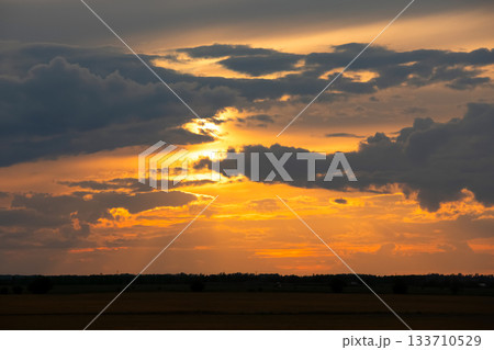 Dramatic orange sunset light in the sky over autumn prairies. 133710529
