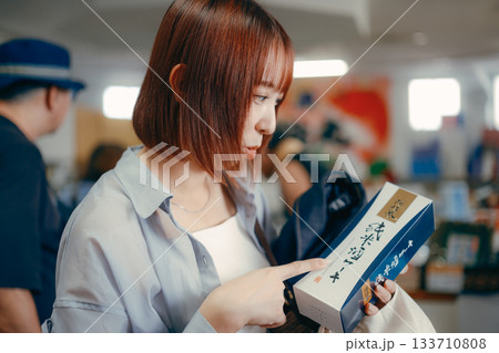 お土産コーナーで商品を手に取る女性 133710808