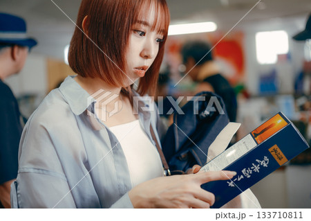 お土産コーナーで商品を手に取る女性 133710811