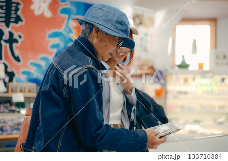 店内で商品を手に取って確認する親子二人 133710884