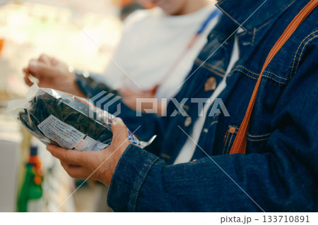 店内で商品を手に取って確認する親子二人 133710891