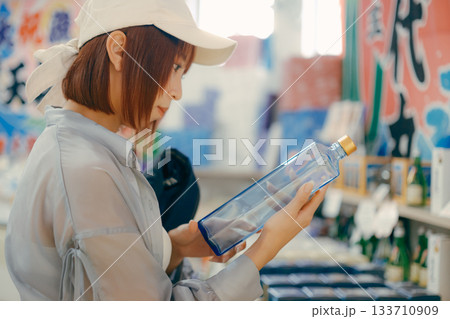 店内でボトルを手に取り眺める女性 店内でボトルを手に取り眺める女性 133710909