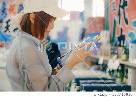 店内でボトルを手に取り眺める女性 店内でボトルを手に取り眺める女性 133710910
